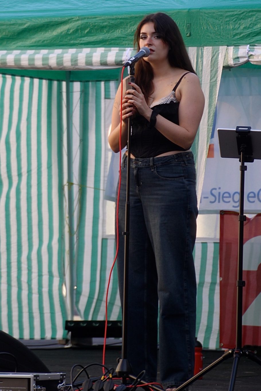 MADDY singt bei einem Live-Auftritt im Freien am Mikrofon