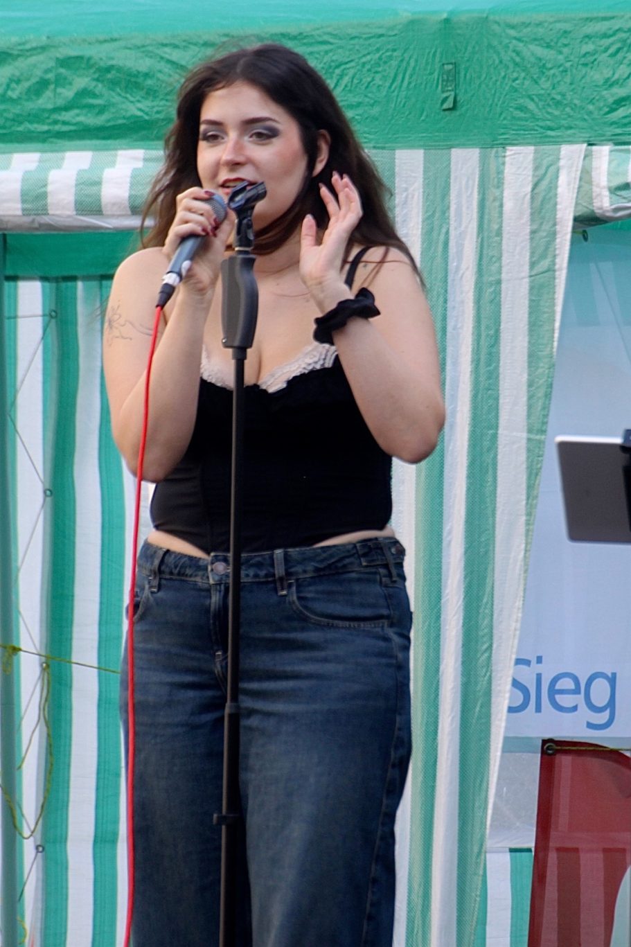 MADDY singt bei einem Live-Auftritt im Freien ins Mikrofon