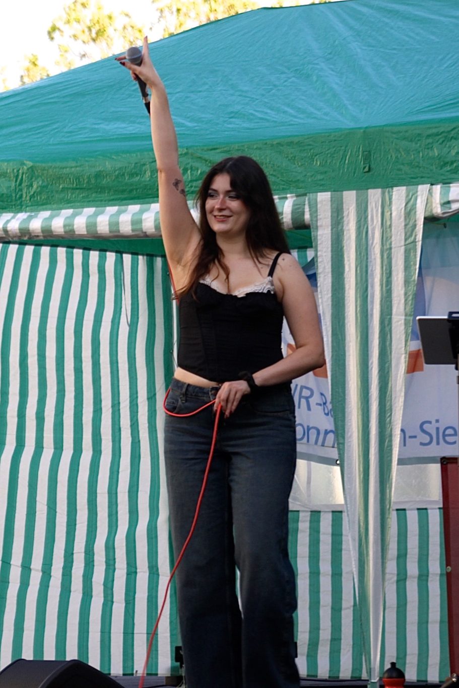 MADDY bei einem Live-Auftritt im Freien mit erhobenem Mikrofon